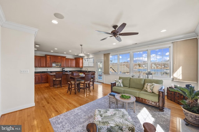 living area featuring light wood-type flooring, crown molding, and recessed lighting