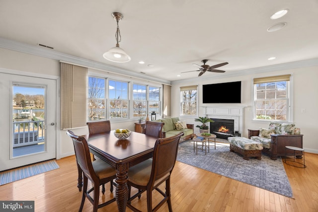 dining room with visible vents, ornamental molding, a lit fireplace, light wood-type flooring, and recessed lighting