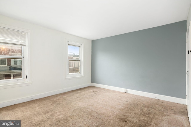 carpeted empty room featuring baseboards