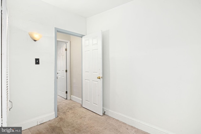 interior space with baseboards and light colored carpet