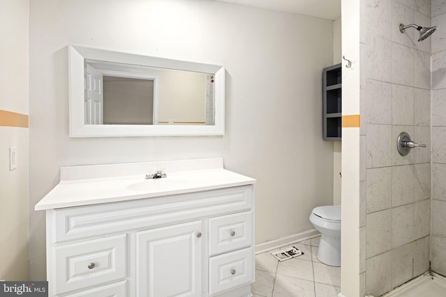 full bath with toilet, baseboards, a tile shower, and vanity