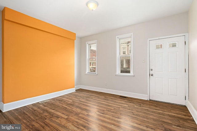 spare room featuring visible vents, dark wood finished floors, and baseboards