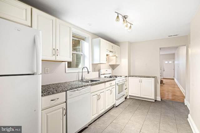 kitchen with white appliances, white cabinetry, a sink, and under cabinet range hood