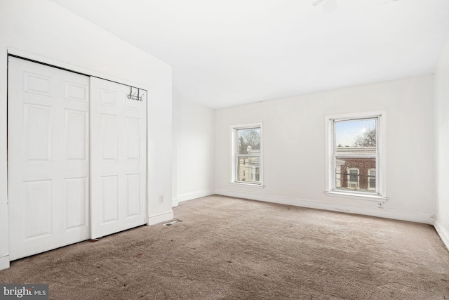 unfurnished bedroom with carpet, visible vents, baseboards, and a closet