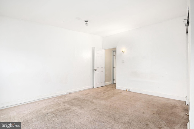 empty room featuring light colored carpet and baseboards