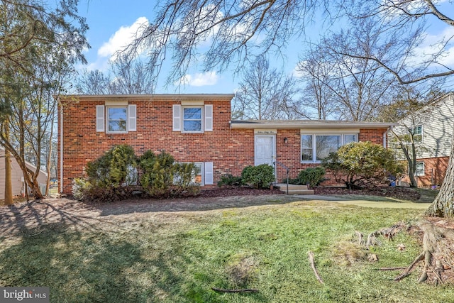 tri-level home with a front yard and brick siding