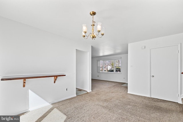 carpeted spare room featuring baseboards and a notable chandelier