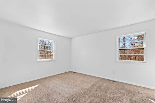 carpeted spare room with visible vents and baseboards