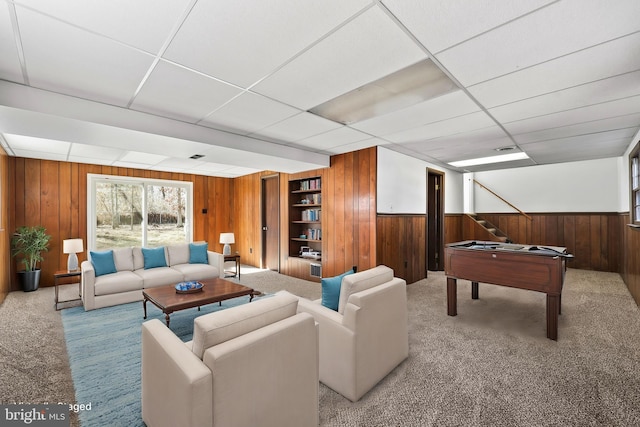 interior space featuring a paneled ceiling, a wainscoted wall, carpet, and wooden walls