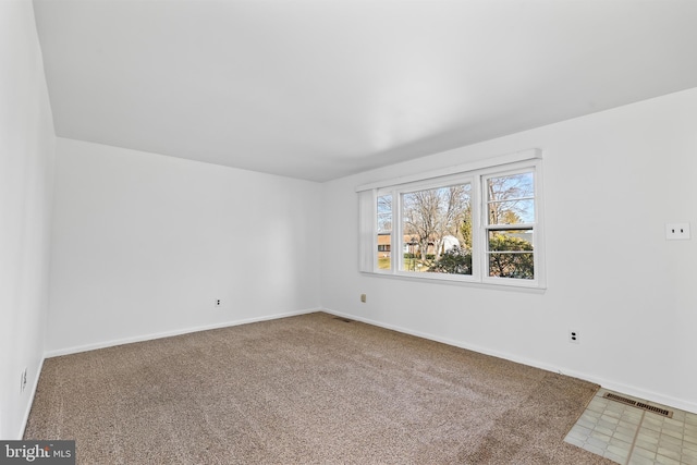 spare room featuring carpet floors, visible vents, and baseboards