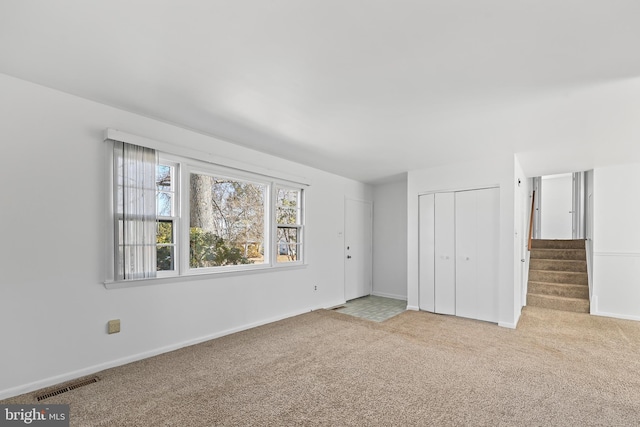 unfurnished bedroom featuring a closet, visible vents, light carpet, and baseboards