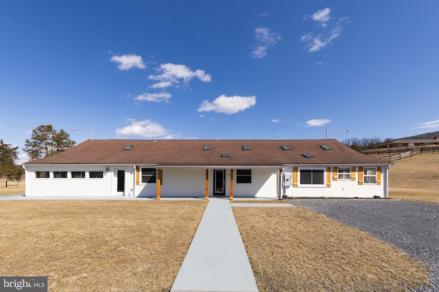 ranch-style house featuring a front yard, covered porch, and stucco siding