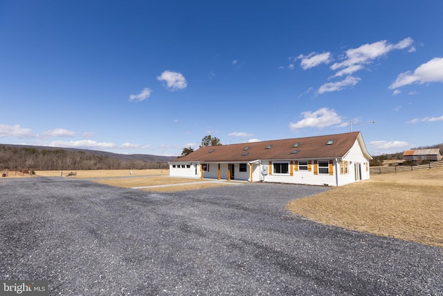 view of front of property featuring gravel driveway and fence