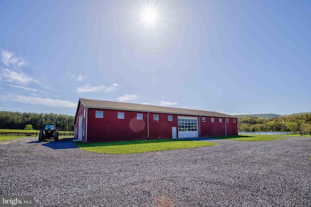 view of pole building featuring fence, a water view, and gravel driveway