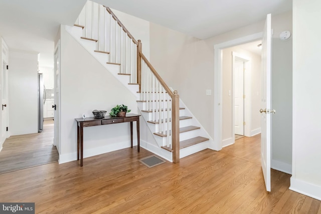 staircase with visible vents, baseboards, and wood finished floors