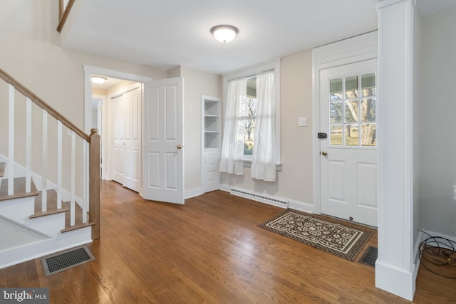 entryway with baseboards, visible vents, wood finished floors, stairs, and baseboard heating