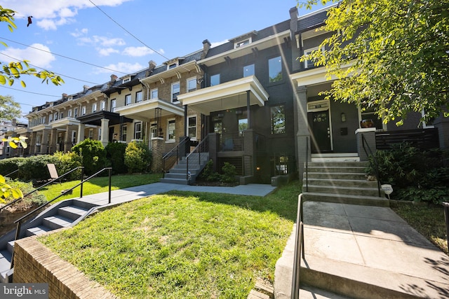 townhome / multi-family property featuring a front yard, brick siding, and a residential view