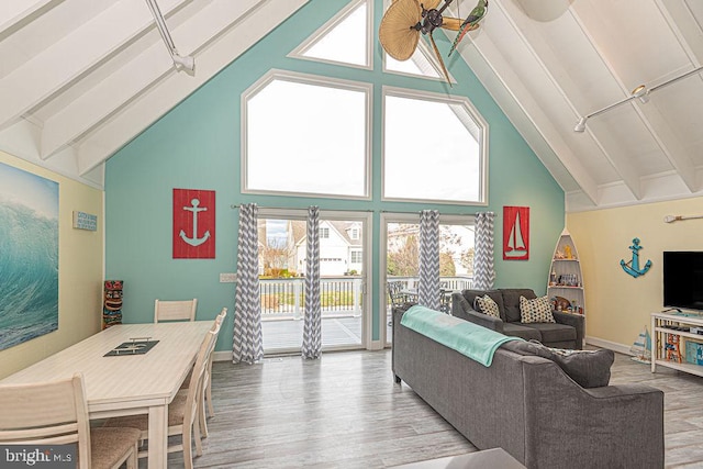 living area with baseboards, high vaulted ceiling, beamed ceiling, and wood finished floors