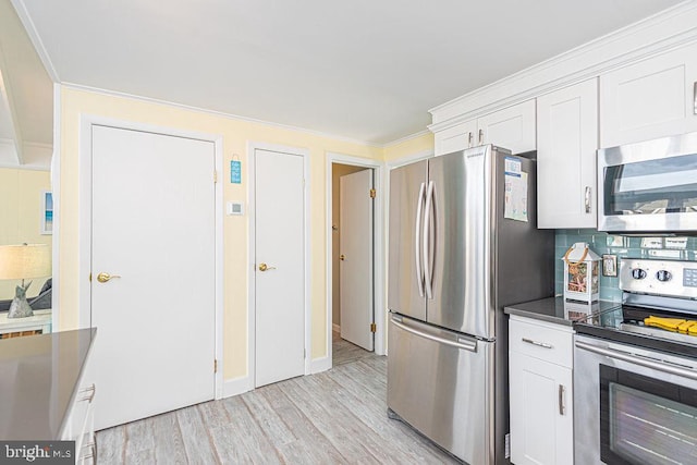 kitchen with decorative backsplash, dark countertops, stainless steel appliances, light wood-style floors, and white cabinetry