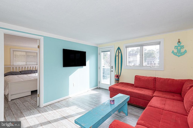 living room with a textured ceiling, wood finished floors, and baseboards