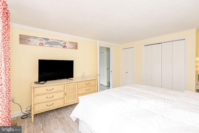 bedroom featuring light wood-style flooring, baseboards, and two closets