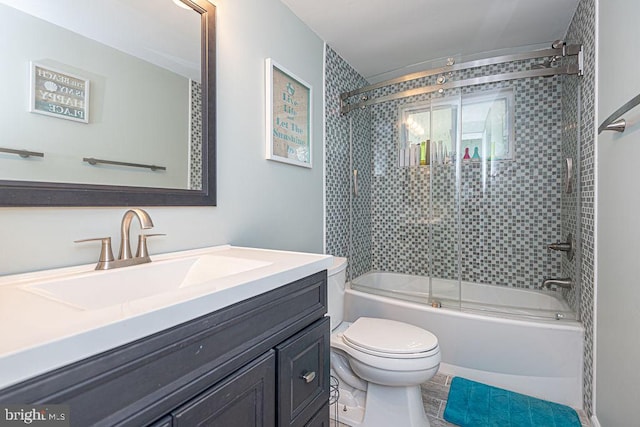 full bath featuring bath / shower combo with glass door, vanity, and toilet