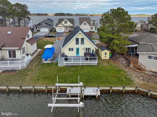 rear view of property with an outbuilding, a yard, boat lift, and a residential view