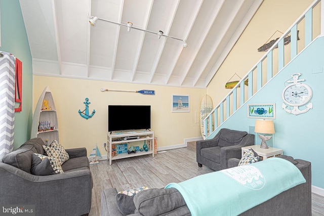 living room with stairs, vaulted ceiling with beams, wood finished floors, and baseboards