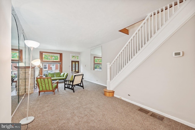 living area featuring carpet, baseboards, stairway, and visible vents