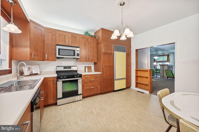 kitchen featuring stainless steel appliances, light countertops, brown cabinetry, and decorative light fixtures