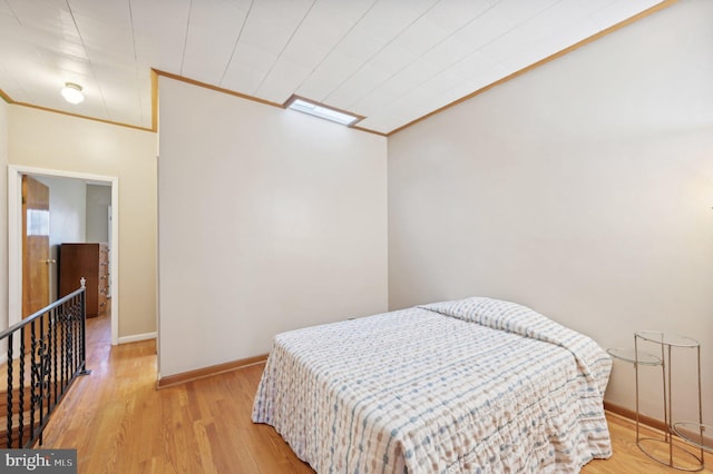 bedroom featuring ornamental molding, light wood-style floors, and baseboards