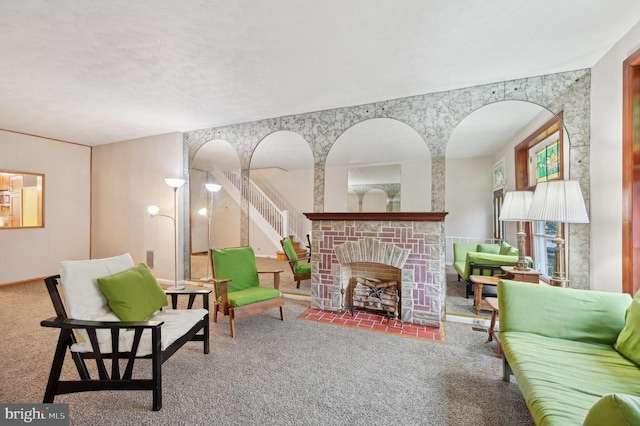 sitting room featuring a textured ceiling, a fireplace, stairway, and carpet flooring