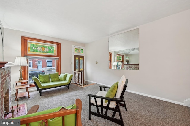 carpeted living room with a brick fireplace and baseboards