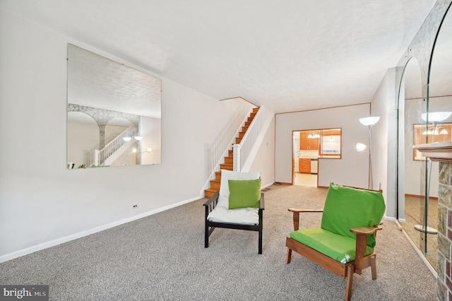 sitting room with carpet, stairway, baseboards, and a textured ceiling