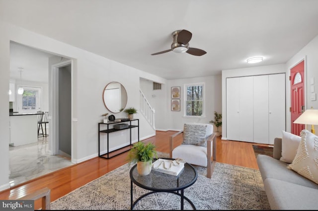 living room featuring baseboards, visible vents, ceiling fan, wood finished floors, and stairs