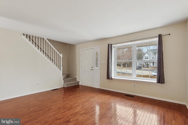 entrance foyer with stairs, wood finished floors, visible vents, and baseboards