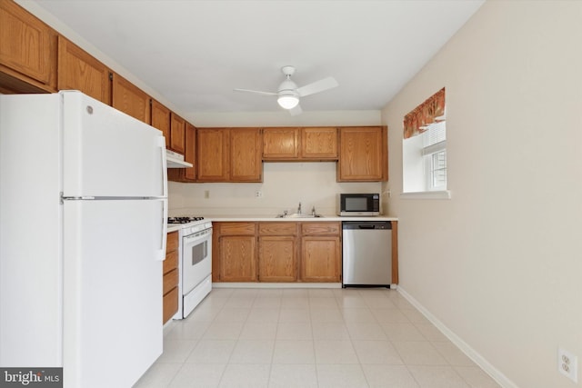 kitchen featuring brown cabinets, stainless steel appliances, light countertops, a sink, and under cabinet range hood