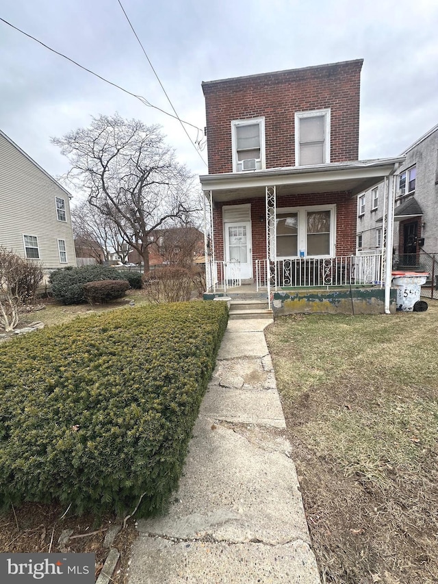 view of front facade with a porch, brick siding, and a front lawn