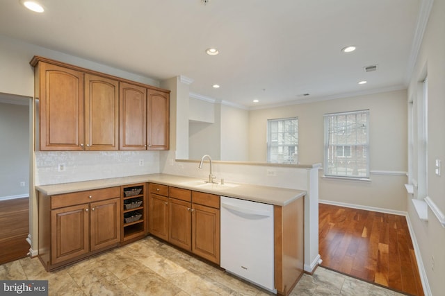 kitchen with visible vents, decorative backsplash, brown cabinets, white dishwasher, and a sink