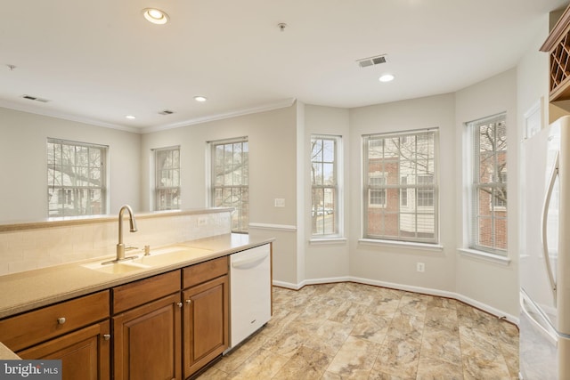 kitchen featuring white appliances, brown cabinetry, a sink, and visible vents