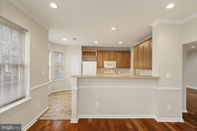 kitchen featuring white appliances, baseboards, ornamental molding, wood finished floors, and a peninsula