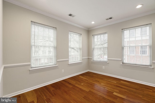 unfurnished room featuring ornamental molding, visible vents, baseboards, and wood finished floors