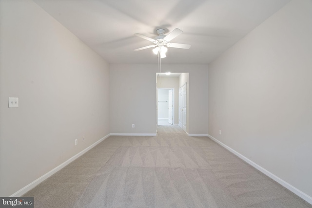 empty room with ceiling fan, light carpet, and baseboards