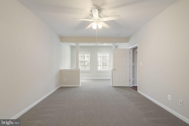 carpeted spare room featuring baseboards and a ceiling fan