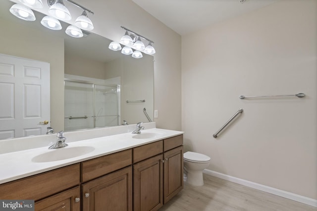 full bath featuring toilet, a stall shower, double vanity, and a sink