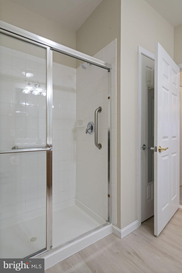 full bathroom featuring a shower stall and wood finished floors