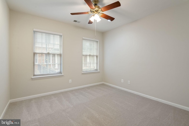 carpeted spare room featuring a ceiling fan, visible vents, and baseboards