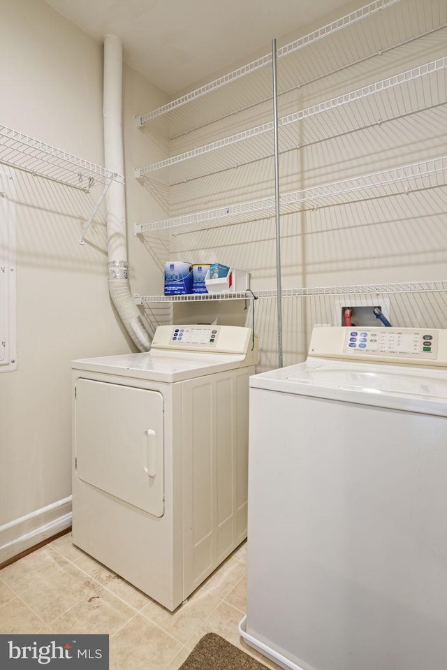 clothes washing area with light tile patterned floors, laundry area, baseboards, and washer and dryer