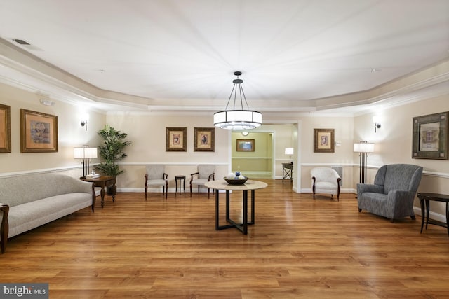 sitting room featuring light wood-type flooring, baseboards, visible vents, and crown molding