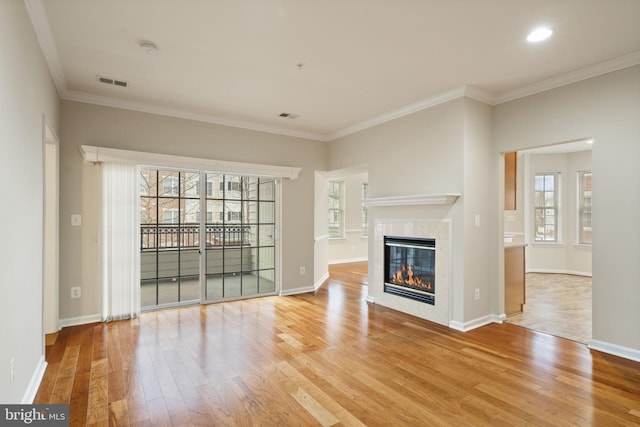 unfurnished living room featuring baseboards, visible vents, ornamental molding, wood finished floors, and a fireplace